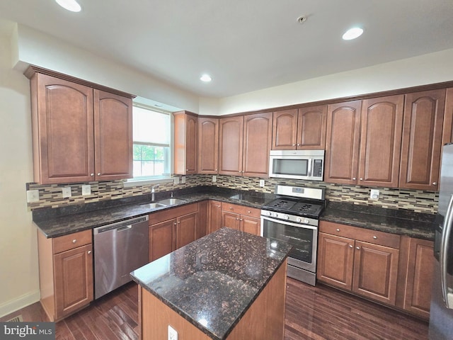 kitchen featuring appliances with stainless steel finishes, dark wood finished floors, decorative backsplash, and a sink