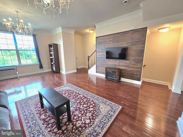 living area with baseboards, hardwood / wood-style flooring, an inviting chandelier, stairs, and crown molding