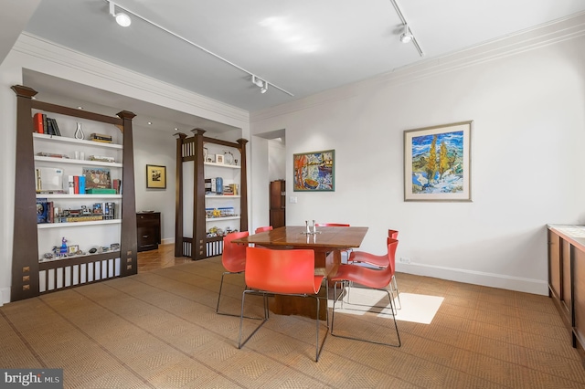 dining area featuring track lighting, baseboards, and crown molding