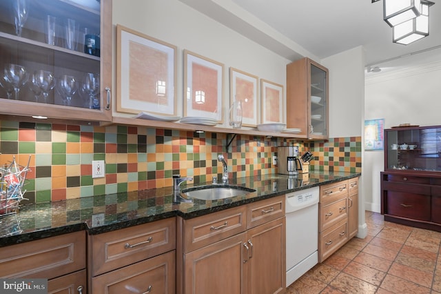 kitchen featuring dark stone counters, glass insert cabinets, a sink, white dishwasher, and backsplash