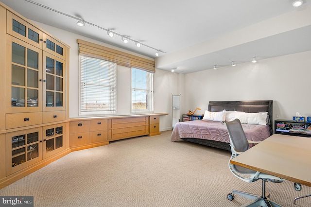 carpeted bedroom featuring track lighting