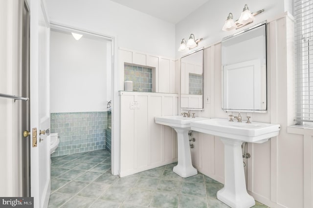 bathroom with toilet, tile walls, and tile patterned floors