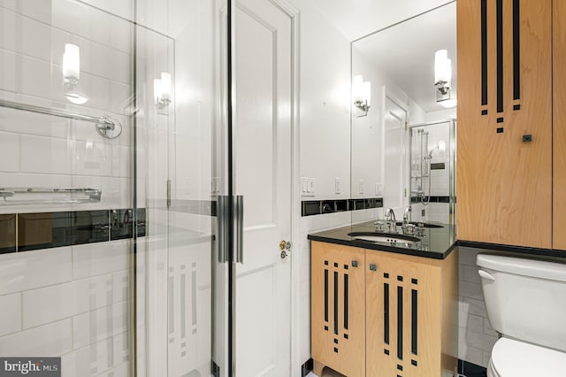 bathroom with tile walls, a shower stall, toilet, and vanity