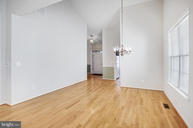 unfurnished dining area featuring a chandelier, visible vents, high vaulted ceiling, and light wood-style flooring