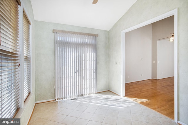 tiled spare room with ceiling fan and vaulted ceiling