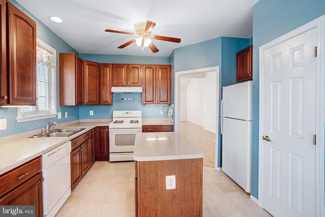 kitchen with under cabinet range hood, white appliances, a sink, light countertops, and a center island