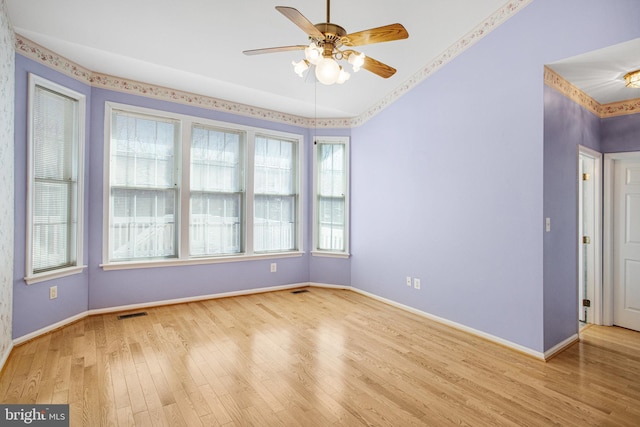 unfurnished room featuring ceiling fan, wood finished floors, visible vents, and baseboards