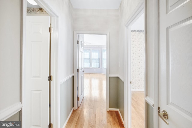 hall featuring light wood-type flooring and baseboards