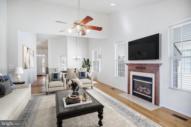 living area featuring high vaulted ceiling, a fireplace, visible vents, and wood finished floors