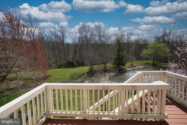 wooden deck with a water view, a yard, and a forest view