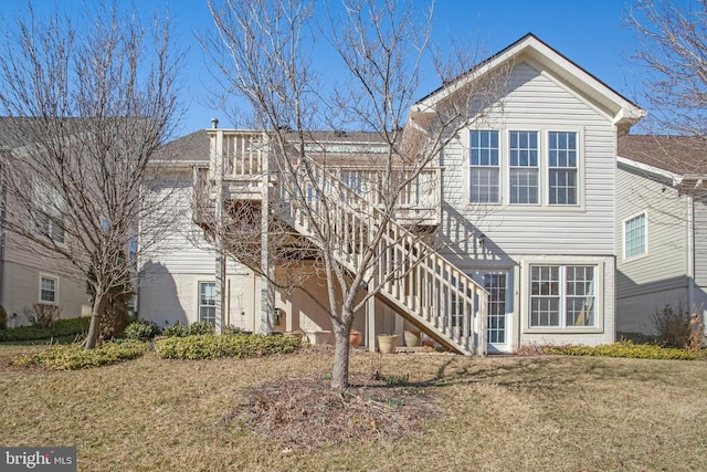 rear view of house featuring stairway and a yard