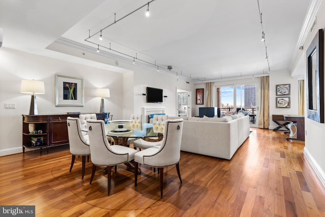 dining area with rail lighting, light wood-style flooring, and crown molding