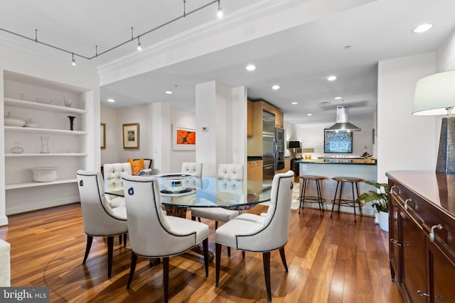 dining room with crown molding, built in shelves, hardwood / wood-style flooring, and recessed lighting