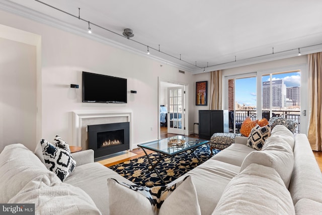 living room with visible vents, a fireplace with flush hearth, wood finished floors, rail lighting, and crown molding