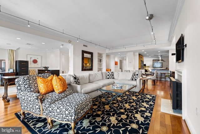 living room featuring light wood finished floors, ornamental molding, visible vents, and rail lighting