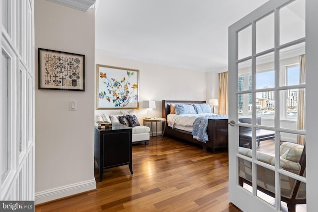 bedroom with crown molding, a view of city, baseboards, and wood finished floors