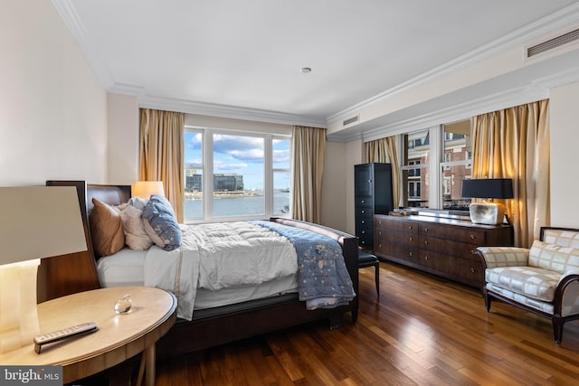 bedroom featuring visible vents, crown molding, and wood finished floors