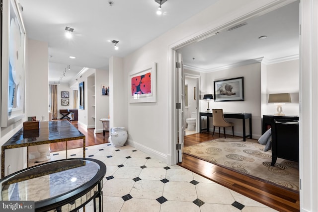 foyer entrance with baseboards, visible vents, crown molding, and wood finished floors