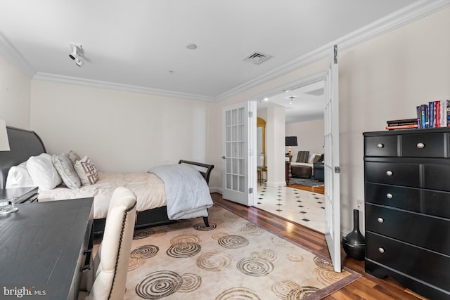 bedroom with french doors, wood finished floors, visible vents, and crown molding