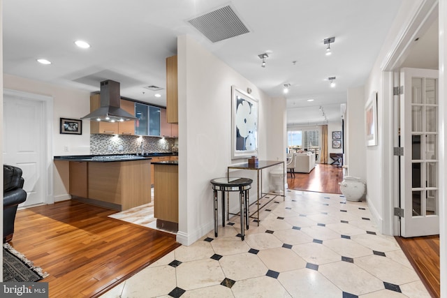 kitchen featuring island range hood, visible vents, decorative backsplash, dark countertops, and modern cabinets