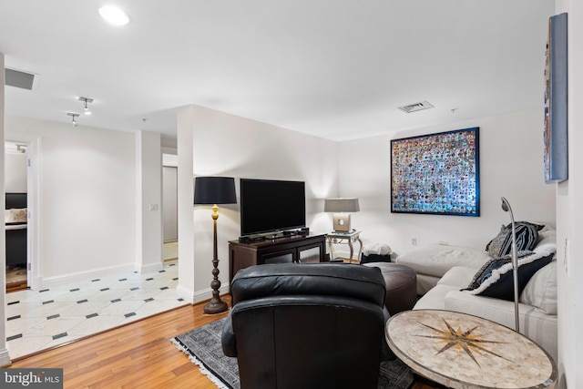 living area featuring light wood-style floors, visible vents, and baseboards