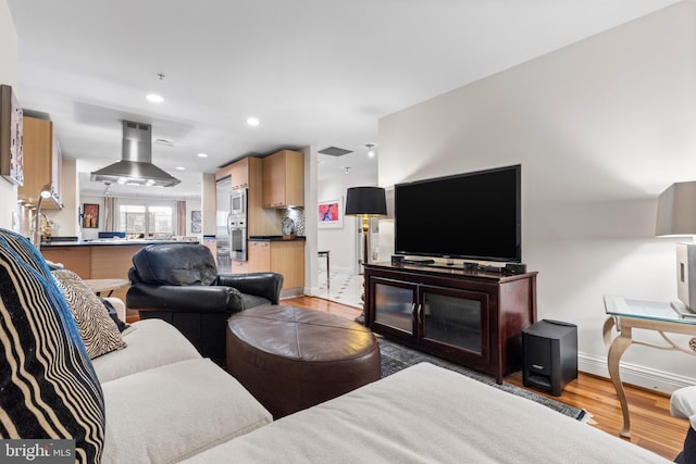 living room with recessed lighting, baseboards, and light wood finished floors