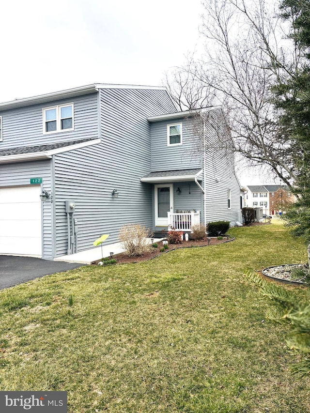 traditional-style home featuring driveway, an attached garage, and a front lawn