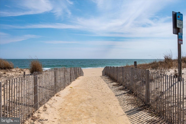 view of water feature with fence and a beach view