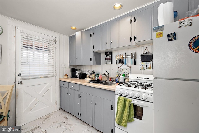 kitchen with marble finish floor, gray cabinets, light countertops, a sink, and white appliances