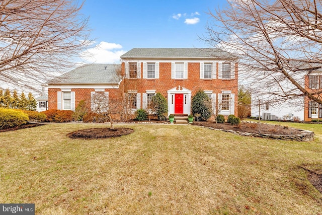 colonial house featuring brick siding and a front lawn