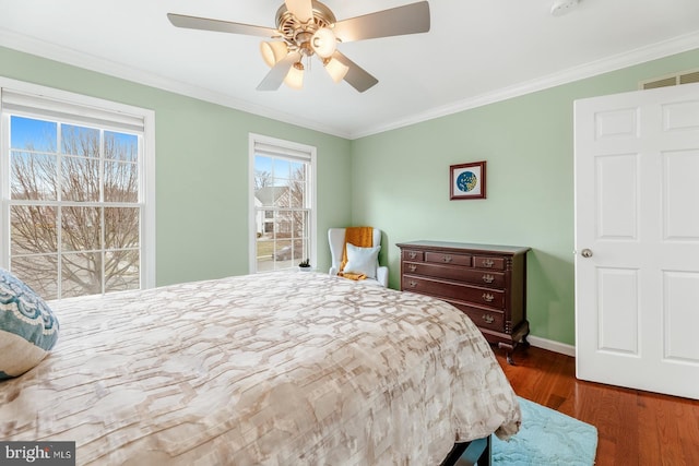 bedroom featuring visible vents, a ceiling fan, wood finished floors, crown molding, and baseboards