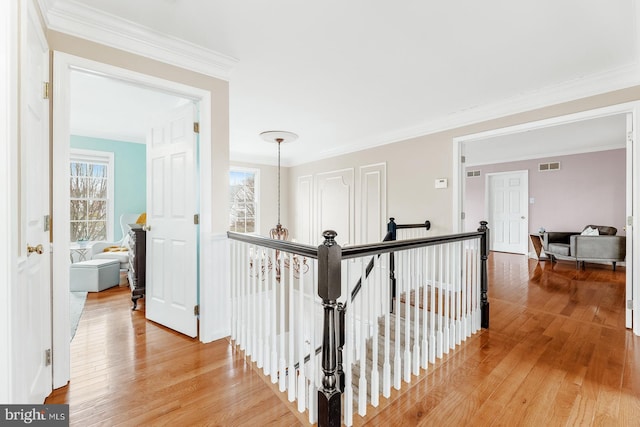 hall featuring light wood-style flooring, plenty of natural light, an upstairs landing, and visible vents