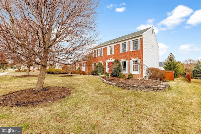 colonial-style house featuring brick siding and a front lawn