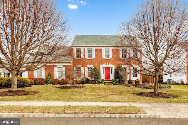 colonial house featuring brick siding and a front yard