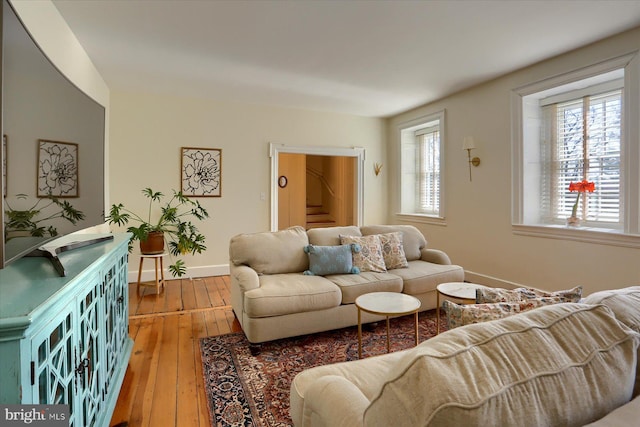 living area featuring wood-type flooring, stairway, and baseboards