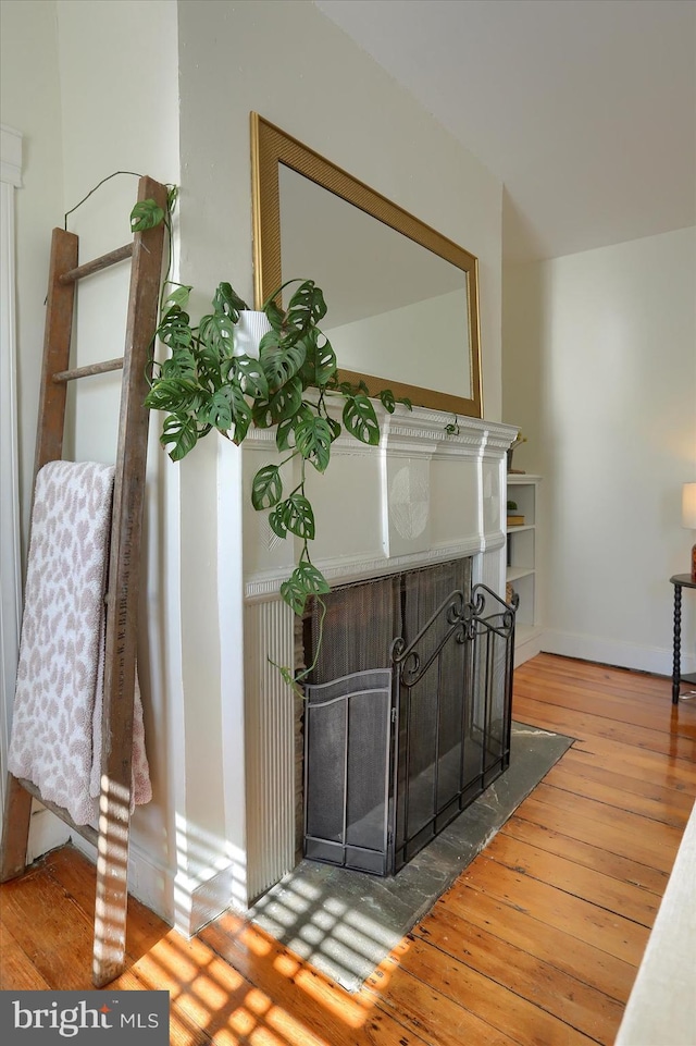 room details with a fireplace with flush hearth, wood finished floors, and baseboards