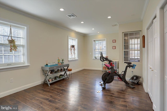 workout area featuring baseboards, wood finished floors, visible vents, and crown molding