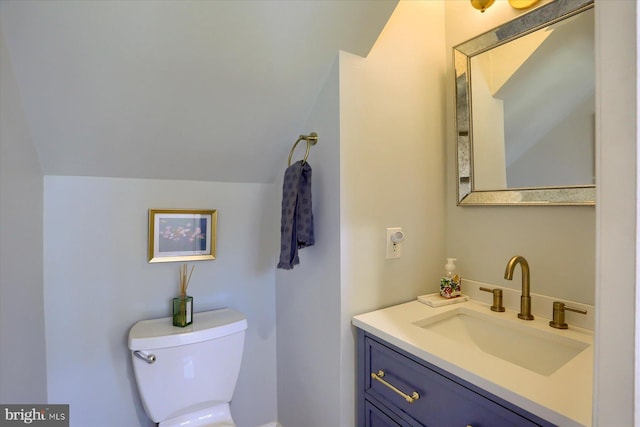 bathroom with toilet, vaulted ceiling, and vanity