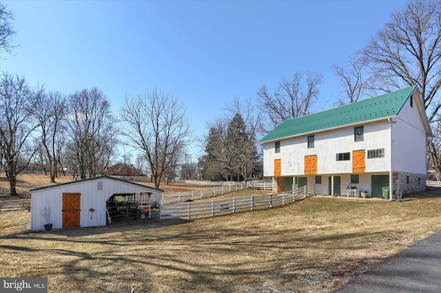 exterior space with an outbuilding, metal roof, fence, a pole building, and an exterior structure