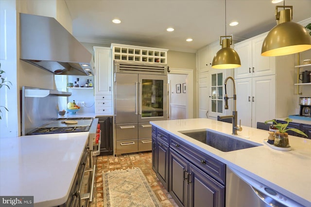 kitchen featuring a sink, high quality appliances, white cabinets, light countertops, and range hood