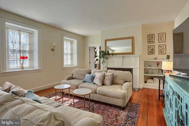 living area featuring hardwood / wood-style flooring, a fireplace, and baseboards