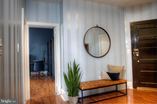 hallway featuring wood finished floors and wallpapered walls