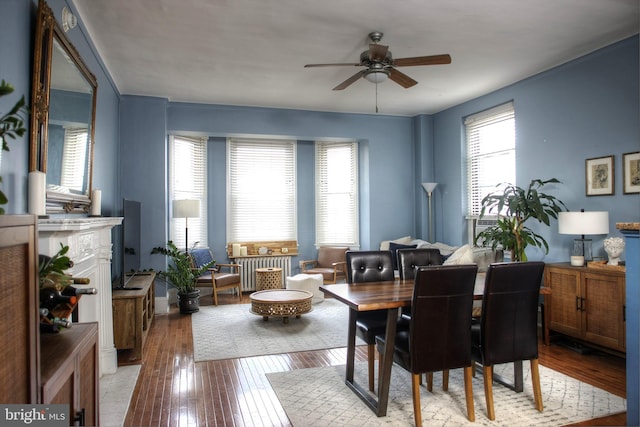 dining area with a fireplace, a ceiling fan, and hardwood / wood-style floors