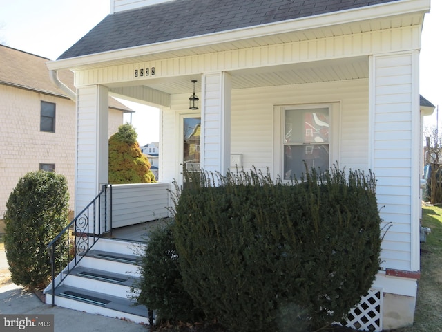 property entrance with covered porch and roof with shingles