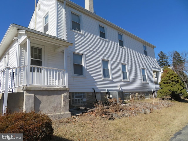 view of side of home with a porch and a chimney