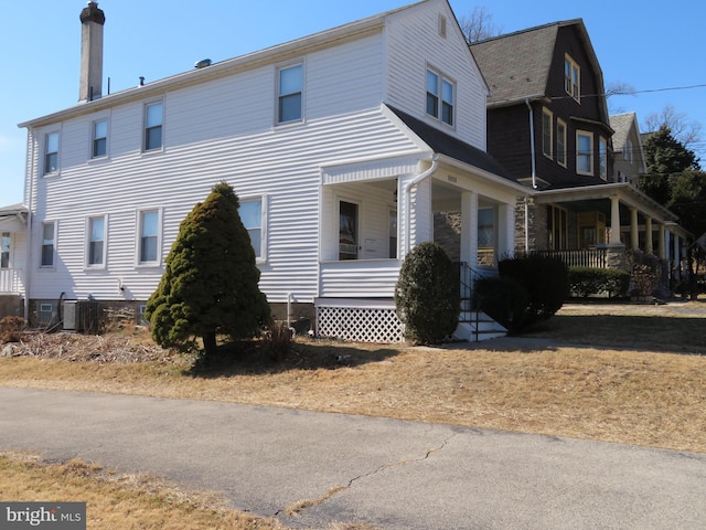 view of property exterior with covered porch, cooling unit, and a gambrel roof