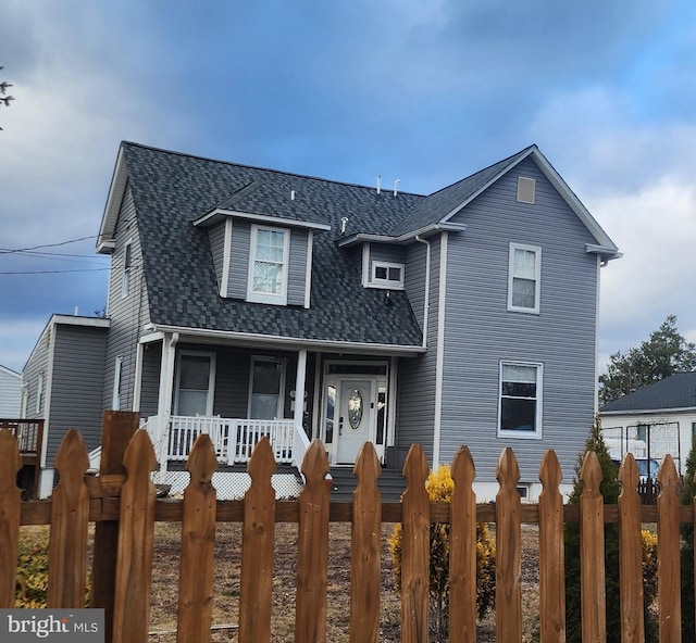 view of front of home featuring a fenced front yard, roof with shingles, and a porch