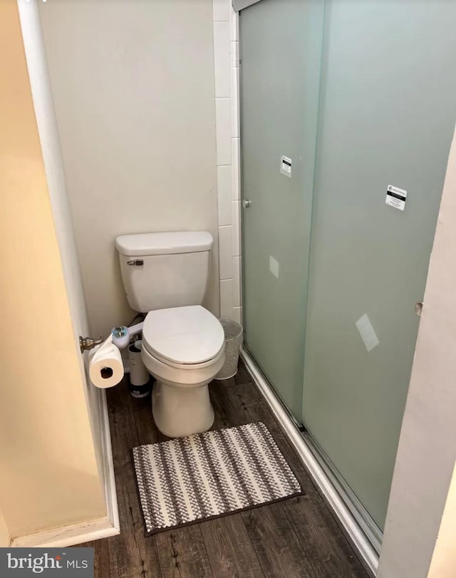 bathroom featuring a stall shower, wood finished floors, and toilet