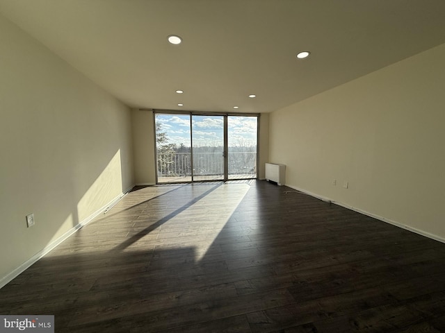 spare room with baseboards, floor to ceiling windows, dark wood-style flooring, and recessed lighting