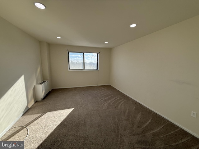 carpeted empty room featuring radiator heating unit, baseboards, and recessed lighting